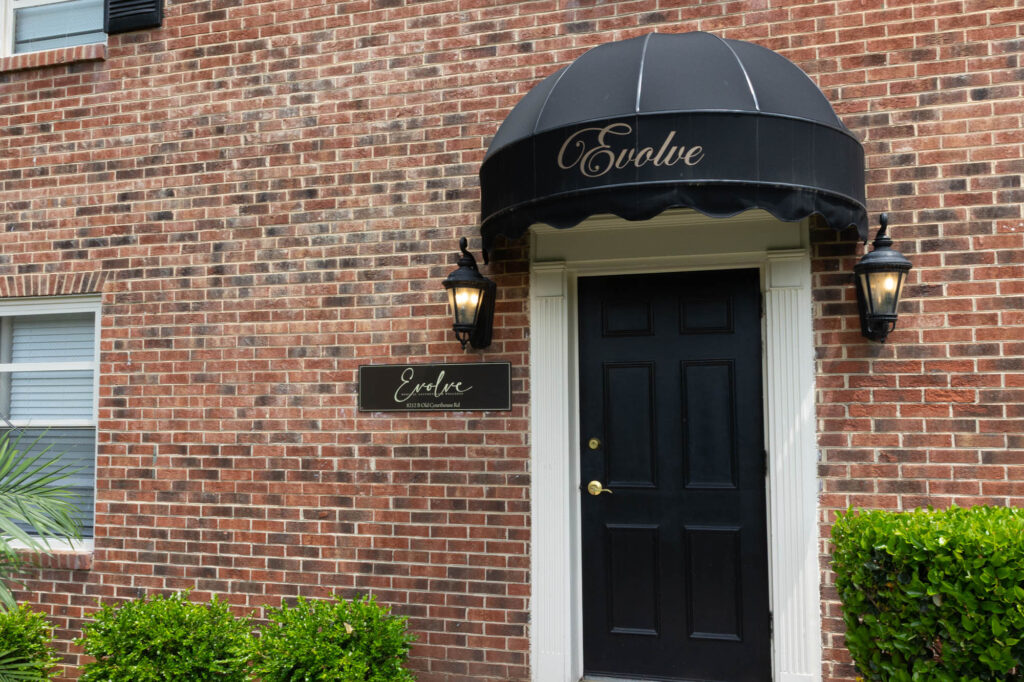 The front door to Evolve, with its black French-style awning and brick surrounding. This is where patients come for sun damage removal in Vienna.