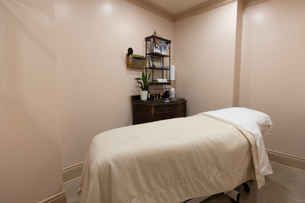Treatment room for patients coming into Evolve Med Spa + Wellness for laser for sun damage in Vienna. There is a spa treatment table with sheets and a pillow placed on top for patient's comfort.